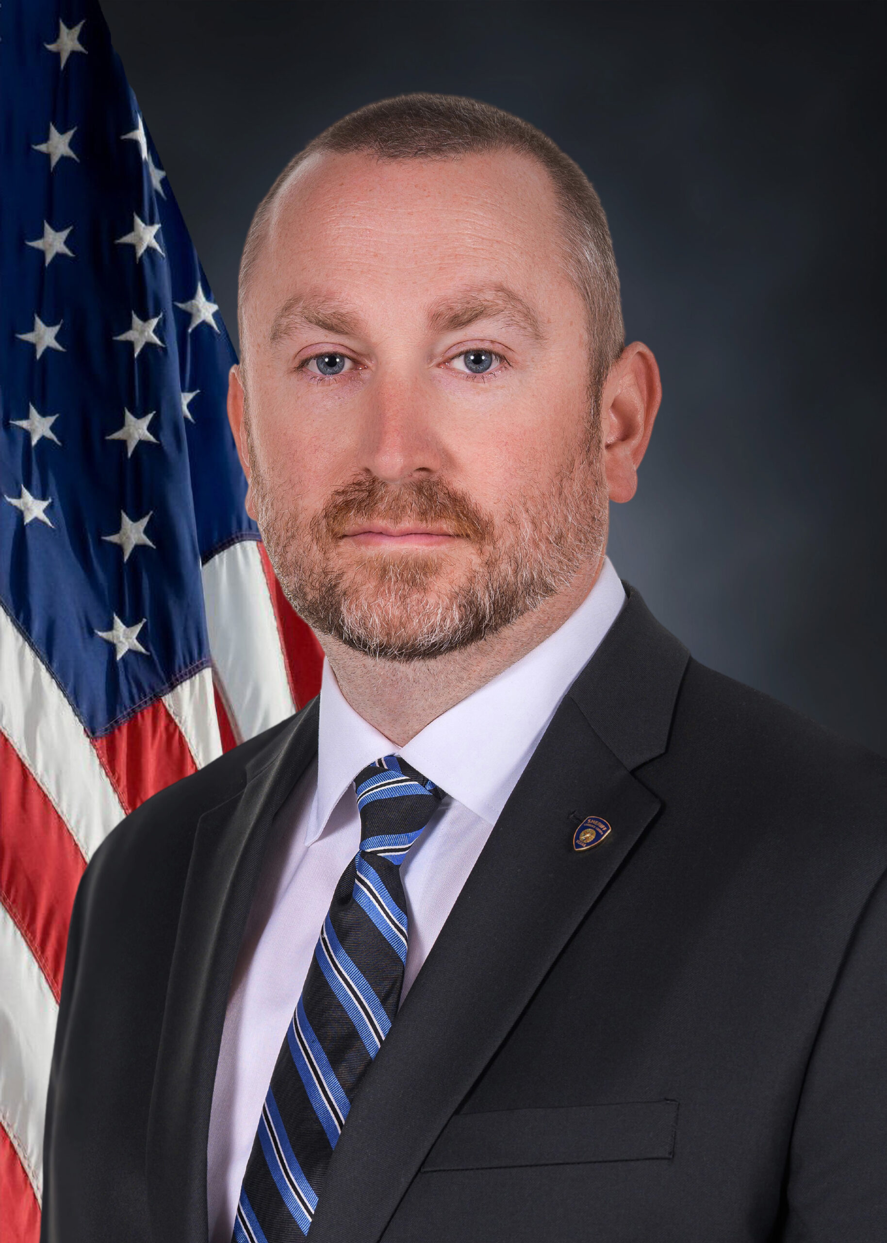 Man in a suit in front of an American Flag
